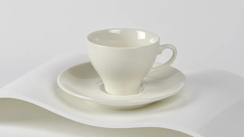 Keramiktasse mit Untertasse auf weißem Acryl bei weichem Studiolicht